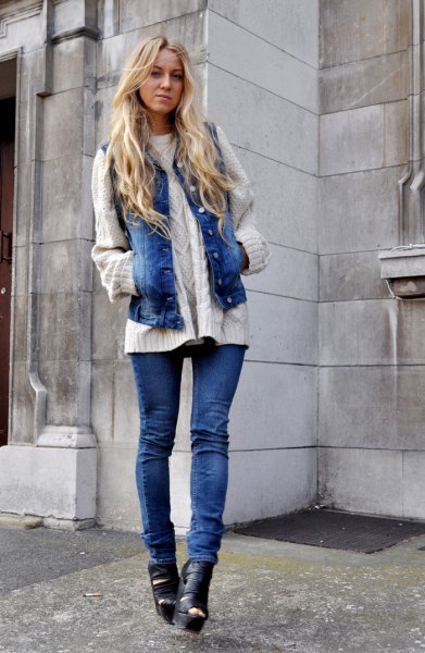white cable knit sweater with blue jeans motorcycle vest and boots