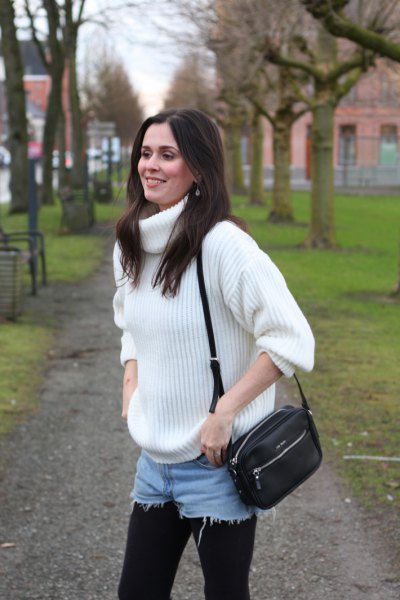 white, thickly ribbed turtleneck sweater with blue denim shorts and leggings