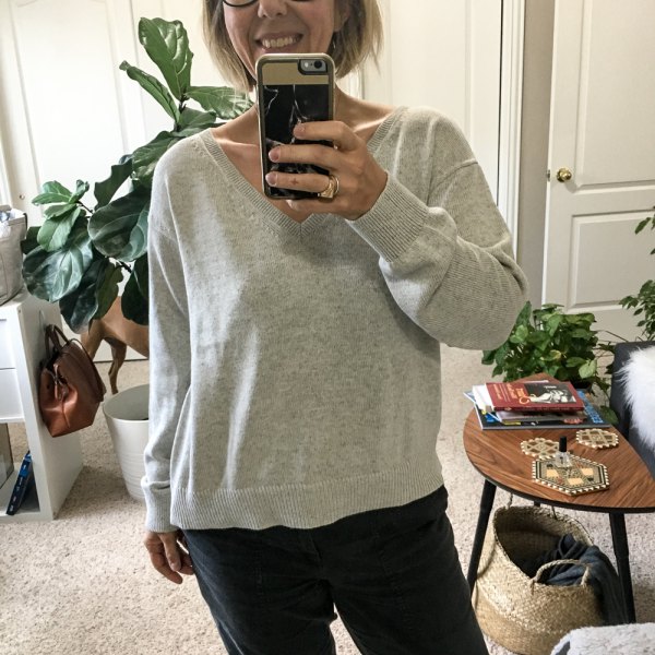 gray cotton sweater with V-neck and black jeans with straight legs