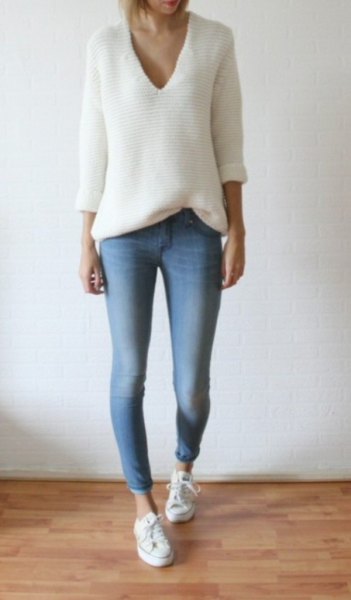 white knitted sweater with a relaxed fit and V-neck and light blue skinny jeans