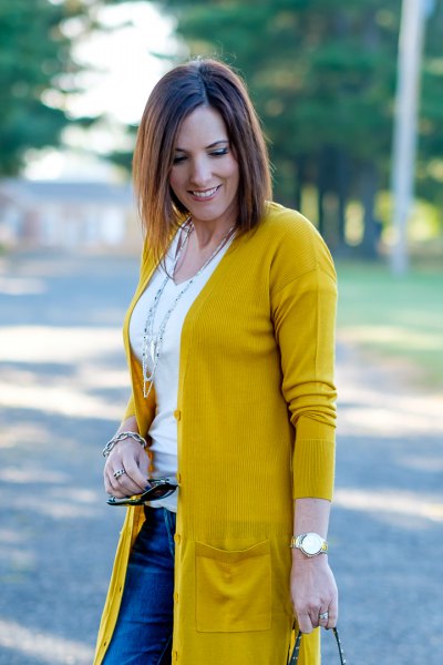 mustard-colored knit sweater with white t-shirt with a scoop neck and blue jeans