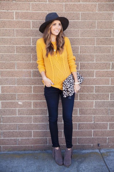 Cable knit sweater with black felt hat and thin dark jeans