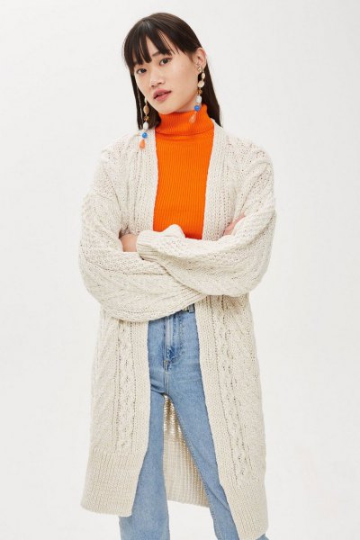 cream-colored long knitted cardigan with orange sweater and mom jeans