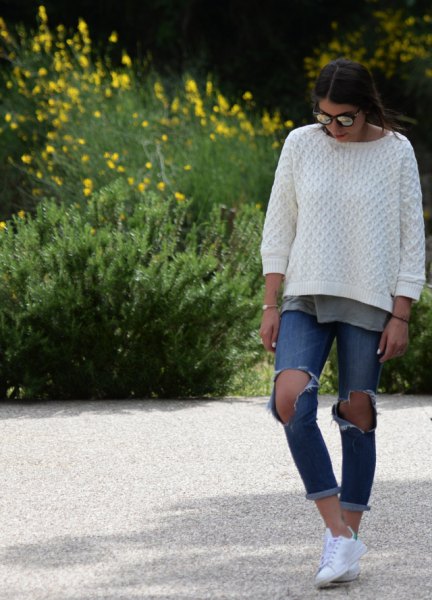 white cable knit sweater with torn and tied blue jeans