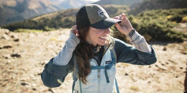 gray hiking jacket with white vest and baseball cap
