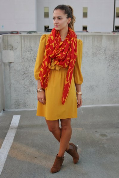 yellow, form-fitting mini dress with orange and gold scarf
