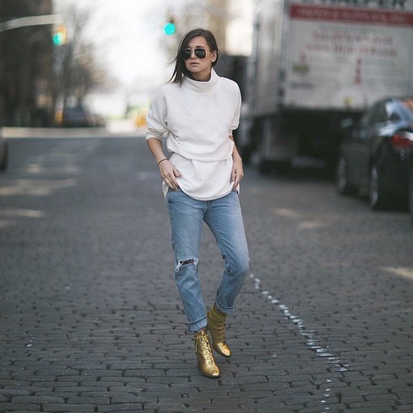 white mock-neck sweater with light blue boyfriend jeans and gold combat boots