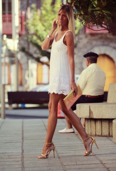 white mini dress with scalloped hem and gold heels with open toes