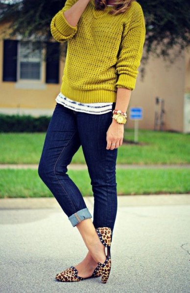 mustard-colored sweater with dark blue skinny jeans with cuffs and flat shoes with animal print