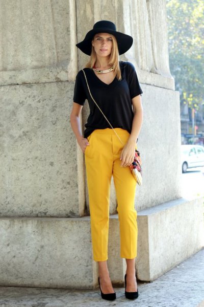 black V-neck t-shirt, floppy hat and short yellow trousers