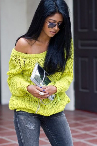 a shoulder yellow sweater with jeans and a silver clutch handbag