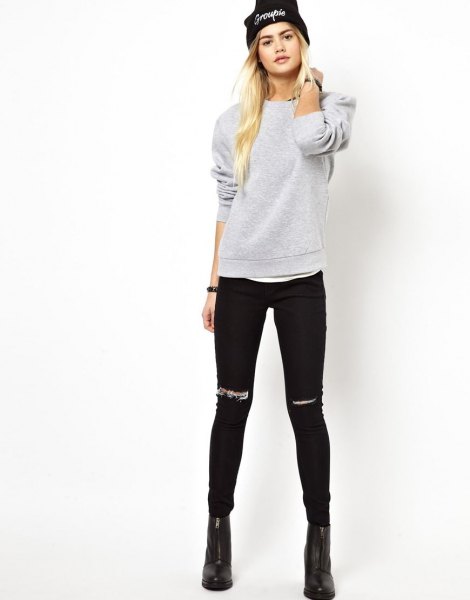 gray sweatshirt with torn black skinny jeans and knitted hat