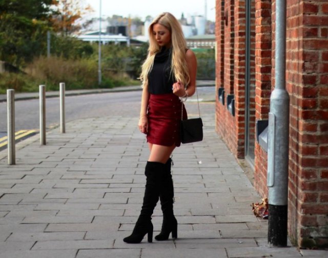 black sleeveless top with stand-up collar, burgundy mini skirt and high boots