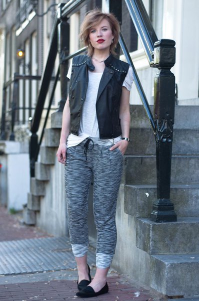 black leather vest with rivets and gray knitted pants