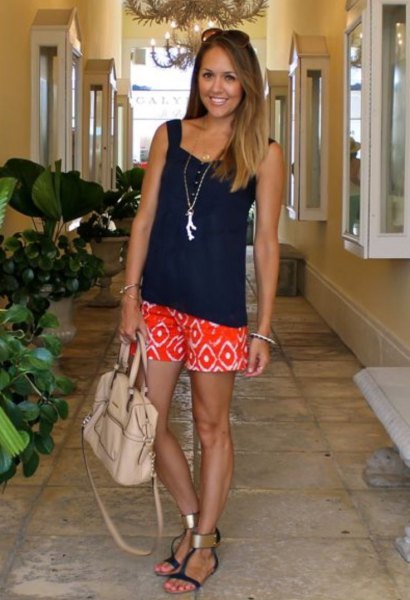 black, loose cut tank top with a heart-shaped neckline and orange shorts with tribal print