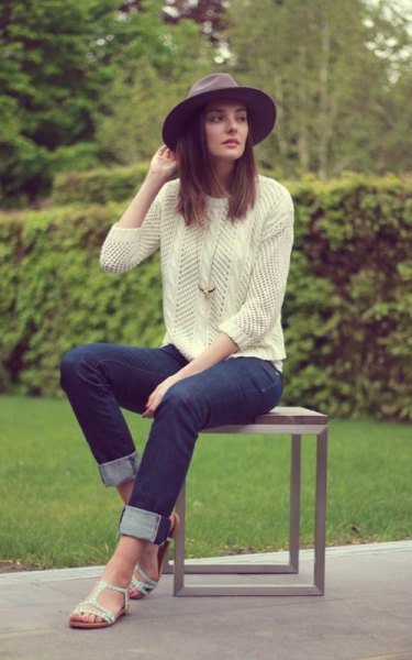Light yellow knit sweater with dark blue slim fit jeans with cuffs and white sandals
