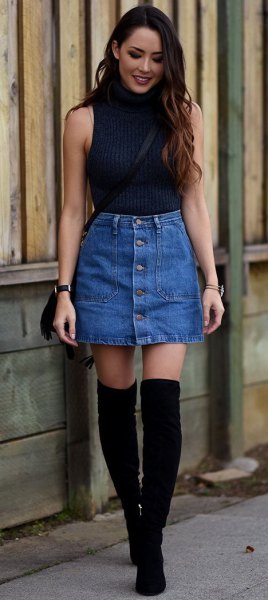 black sleeveless sweater with stand-up collar and blue mini skirt with button front