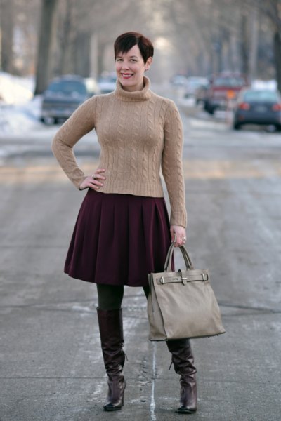 figure-hugging green turtleneck sweater with black pleated skirt and brown tights