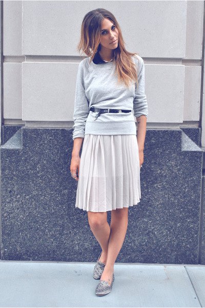 gray sweater with a relaxed fit and knee-length pleated skirt and silver loafers with spikes