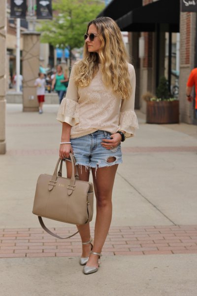 Light pink blouse with bell sleeves and light blue denim shorts with a mini tear