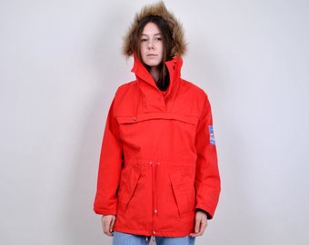 red windbreaker with hood made of faux fur and light blue jeans
