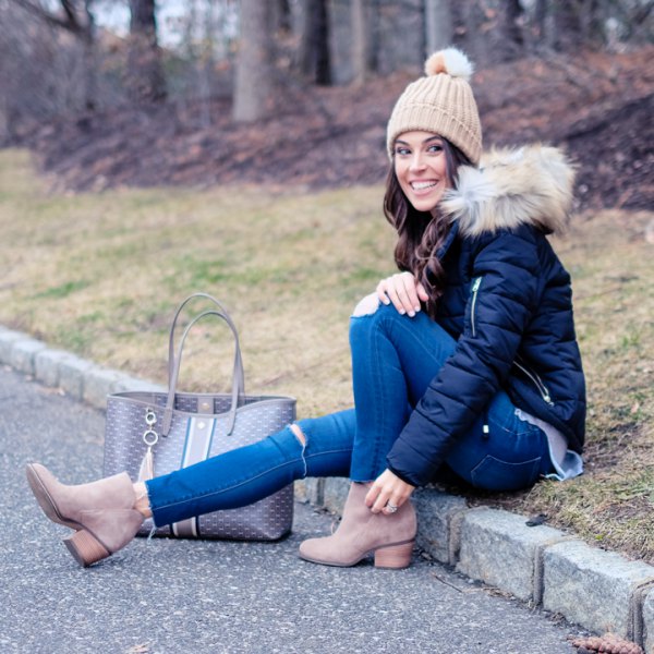 black down jacket with blue skinny ripped jeans and crepe knit hat