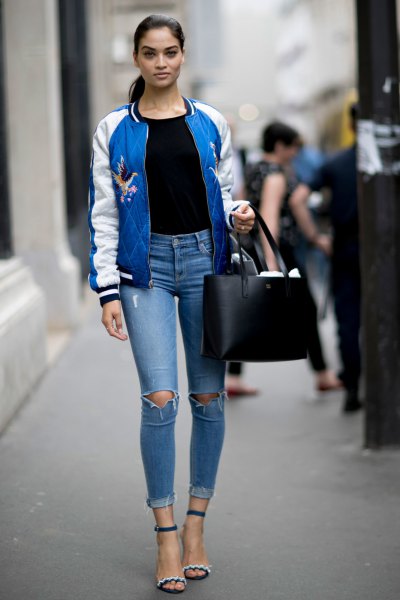 blue and white embroidered bomber jacket with black tee and ripped jeans