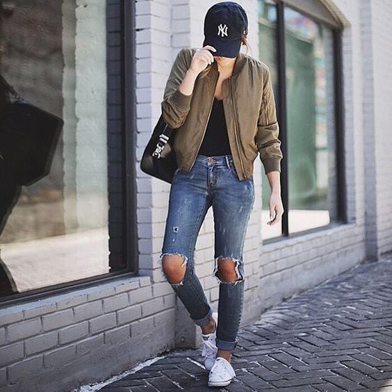 green bomber jacket with black scoop neck top and heavily ripped jeans