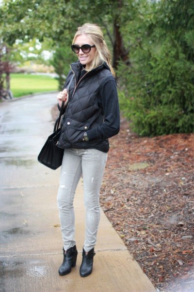 black sweater with quilted puffer jacket and light gray jeans