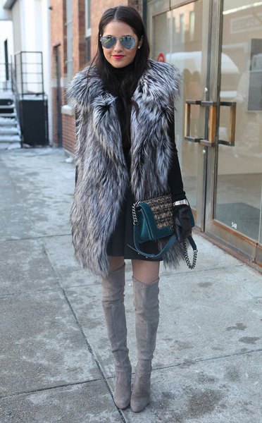 gray long faux fur vest with black sweater dress and high thigh boots