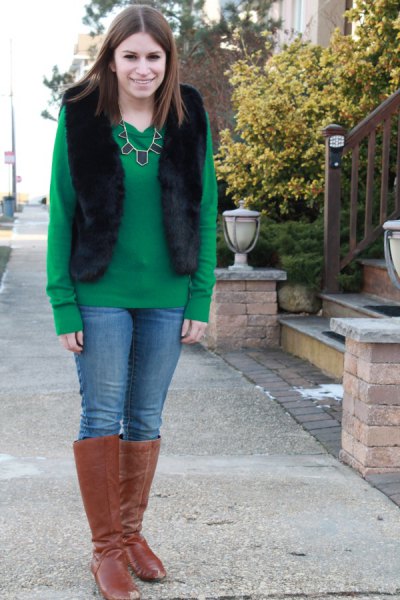 green sweater with black vest and camel high boots in knees
