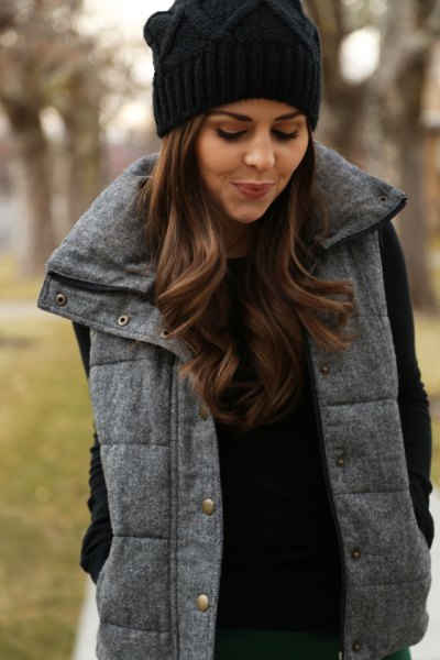 black knitted hat with gray quilted long vest and knitted sweater