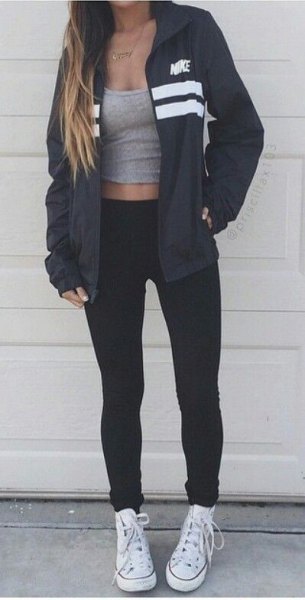 black windbreaker with a gray, short tank top with a scoop neck and white canvas sneakers