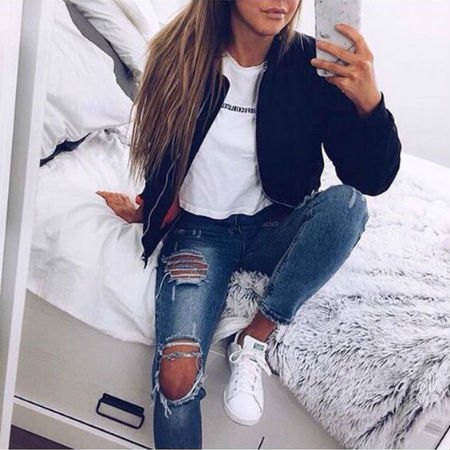 black bomber jacket with a white graphic t-shirt and really torn blue jeans