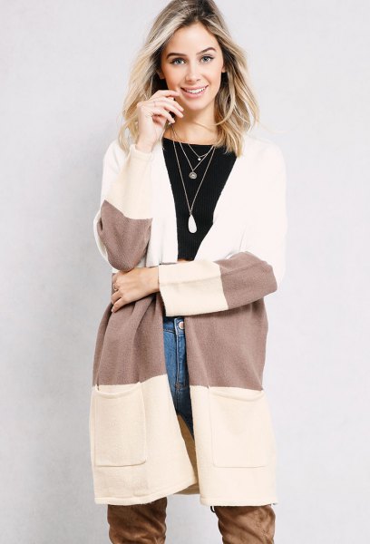 white and gray long cardigan with blue jeans and long camel boots