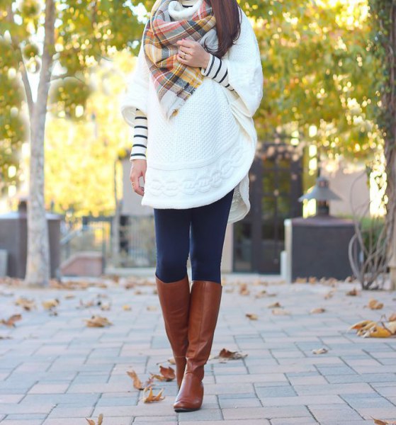 White cable knit cape with a checked scarf and knee-high boots made of brown leather
