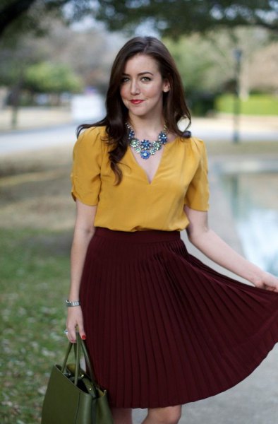 Mustard shirt with a silver statement chain with a burgundy pleated skirt