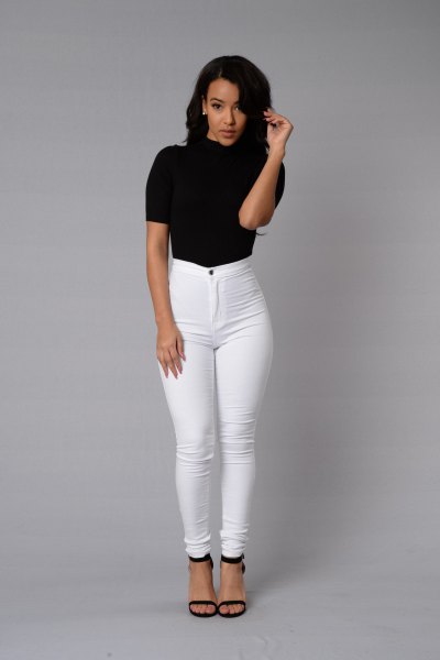 black short-sleeved mock-neck top with white skinny jeans with a high waist