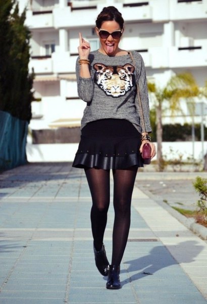 gray graphic sweater with black flared mini skirt and short boots