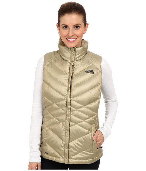 golden down vest with white long-sleeved t-shirt and black jeans