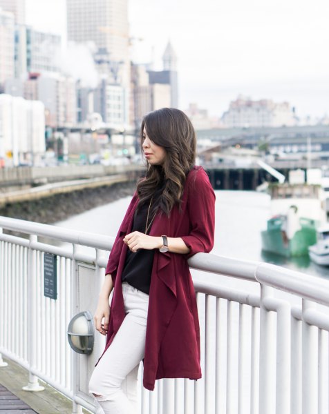 burgundy trench coat with black sweater and white skinny jeans