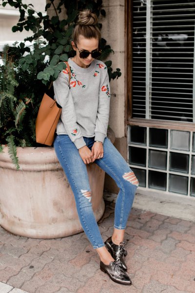 gray embroidered sweater with blue ripped skinny jeans