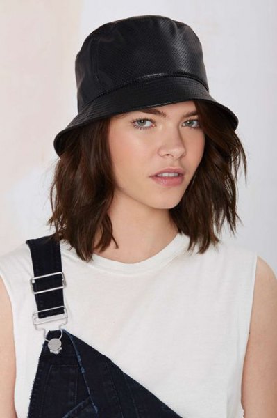 black leather hat with white sleeveless top and denim overalls