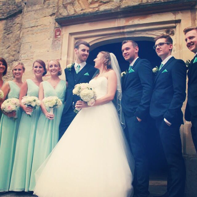 Out side the church, coast mint green bridesmaid dresses & navy .