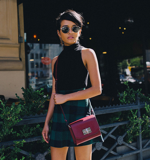 Olivia Lopez is wearing a black knit crop top and a plaid pleated .